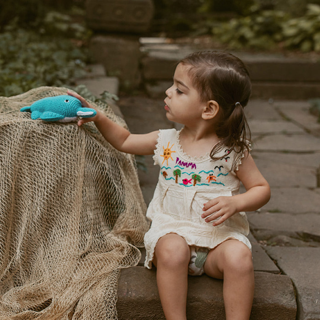 Toddler playing outside with handmade sawfish plush toy