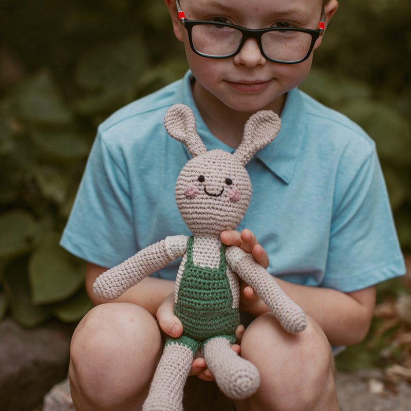 boy holding bunny in green overalls handmade organic cotton